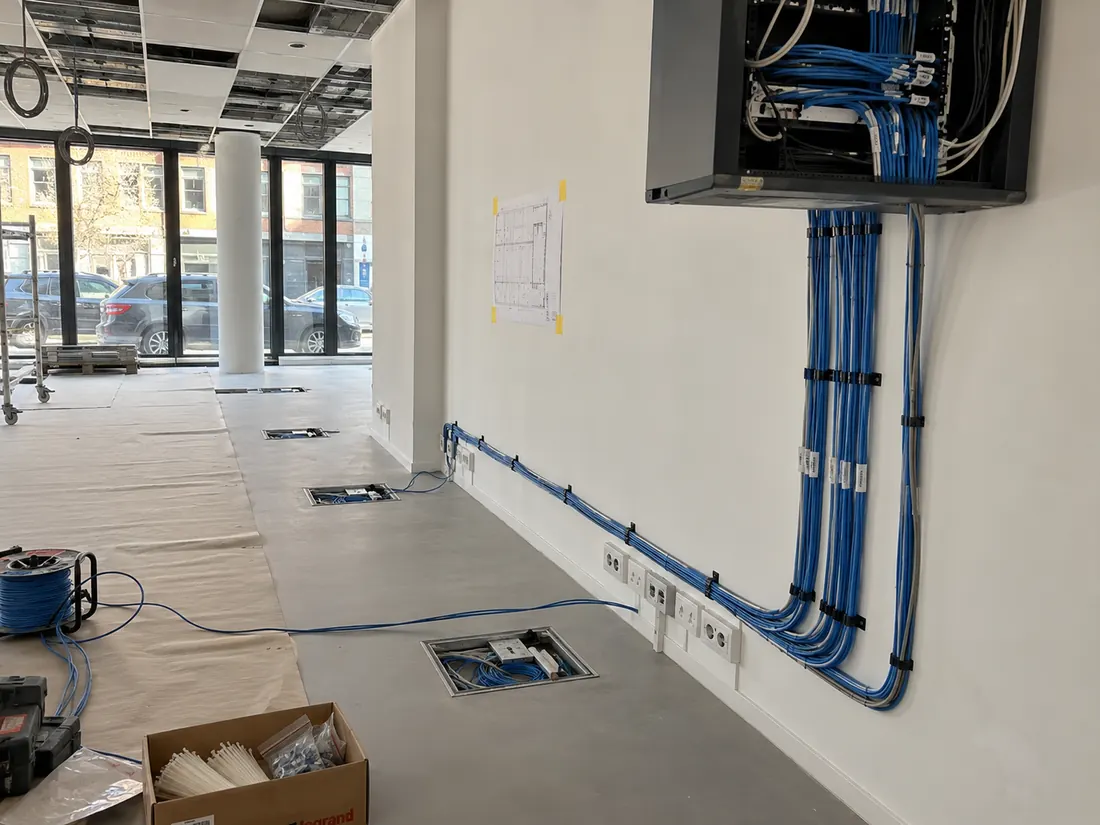 Werffoto kantoor: blauwe netwerkkabels naar de netwerkkast, vloerdozen en stopcontacten langs de muur